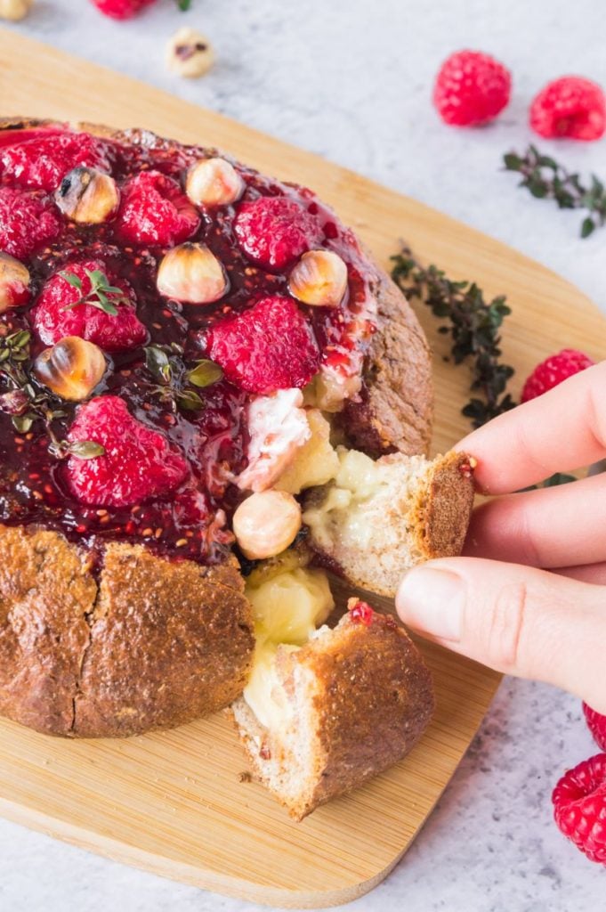 Someone pulling apart a prepared Baked brie with bread