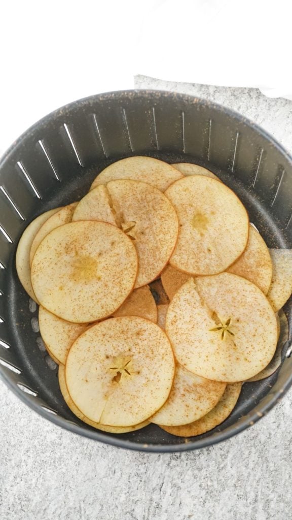 apple slices arranged in the basket of an air fryer