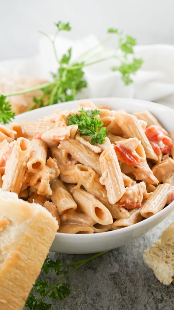 front angle shot of a bowl of creamy pasta with torn baguette on the side