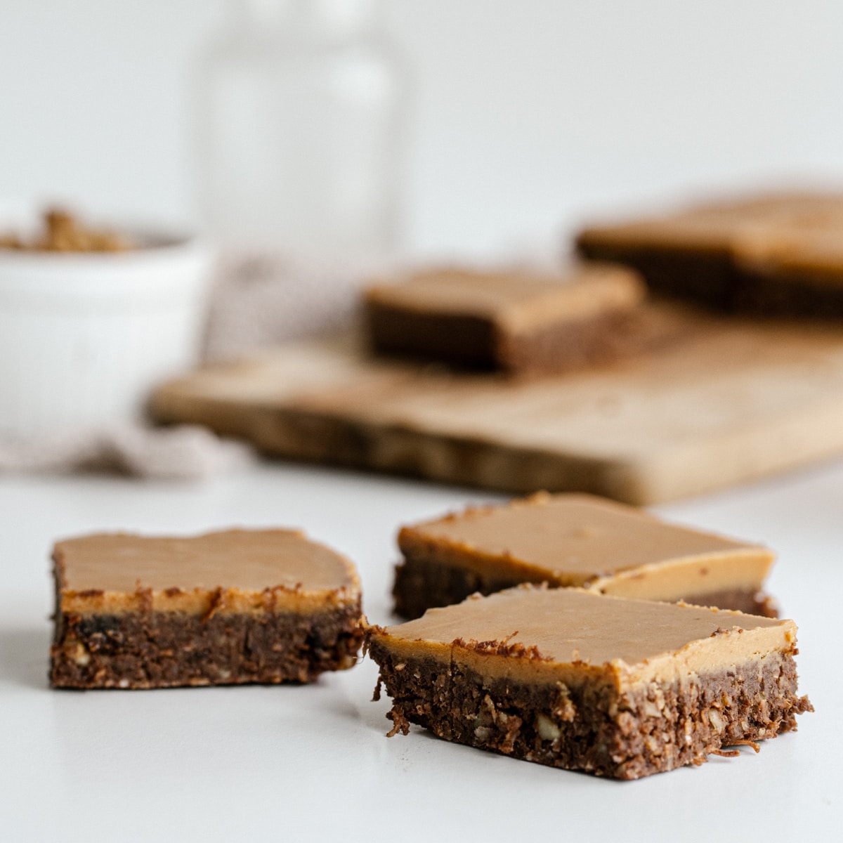 up close shot of vegan brownies on a white background with a chopping board in the background