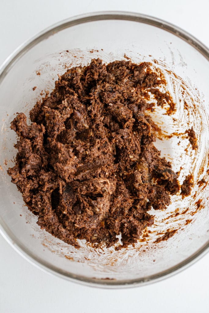 vegan brownie batter ingredients in a clear bowl  after being processed into a sticky consistency