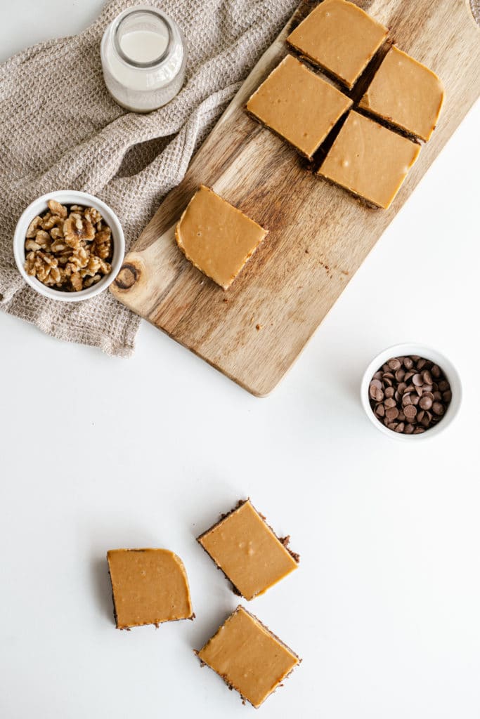 Overhead shot of brownie slices on a  wooden chopping board surrounded by little bowls of ingredients