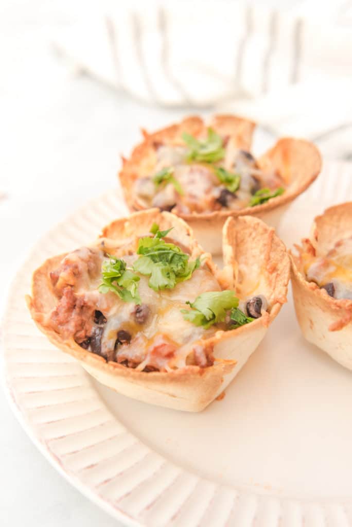 beef enchiladas baked in muffin tin tortillas and topped with cilantro served on a white plate