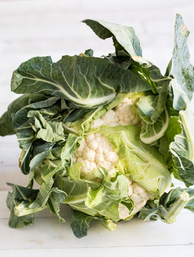A whole cauliflower sitting on a white bench