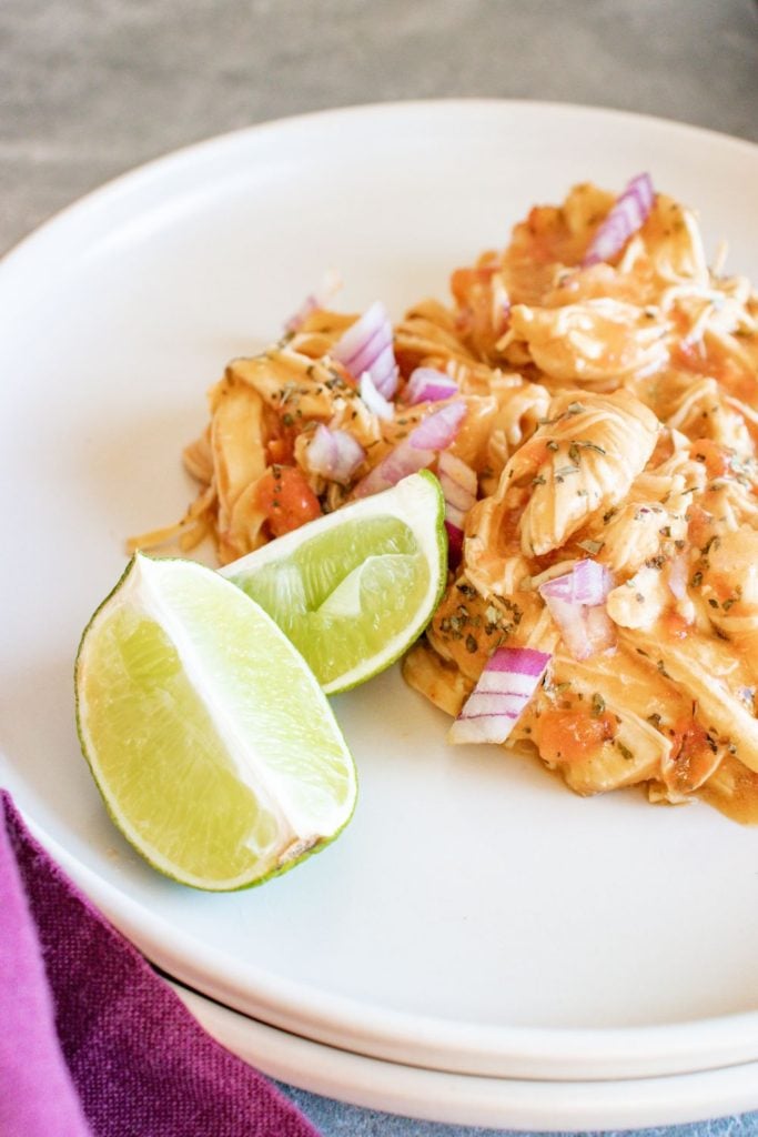 Thai inspired Instant pot chicken breasts served up on a white plate with some lime wedges