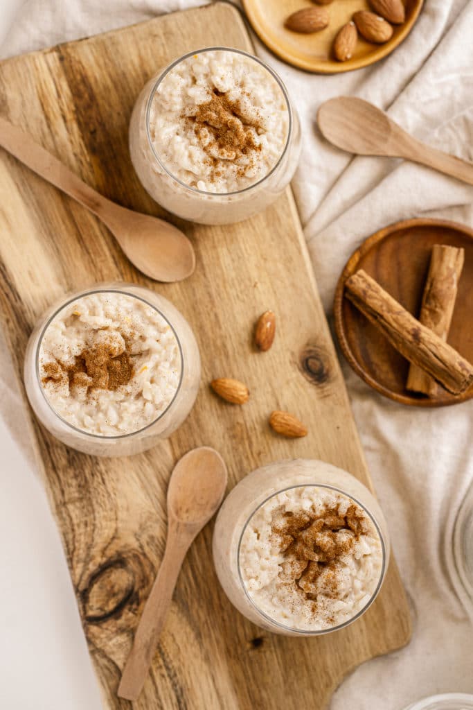 Overhead shot of stovetop rice pudding served up in glasses topped with extra cinnamon and almonds