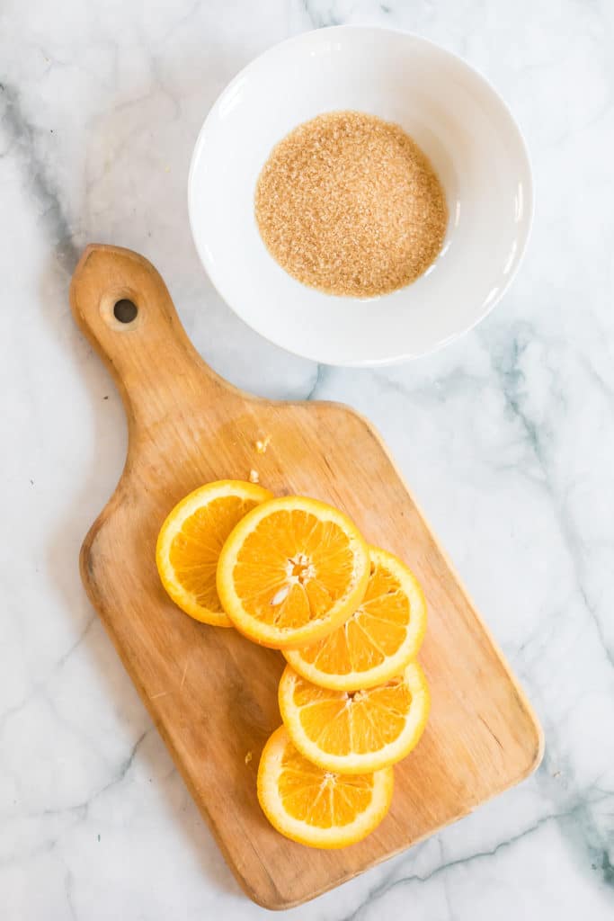 Overhead ingredient shot of sliced oranges and brown sugar for making dehydrated oranges