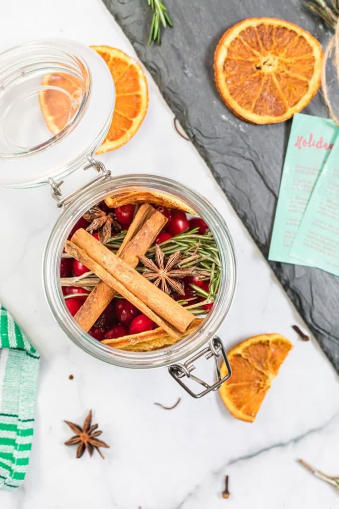 overhead shot of natural potpourri in a glass jar with slices of dehydrated oranges surrounding it.