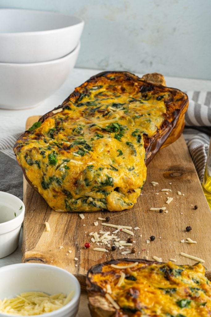 Frontal shot of four cheese stuffed butternut squash on a wooden chopping board