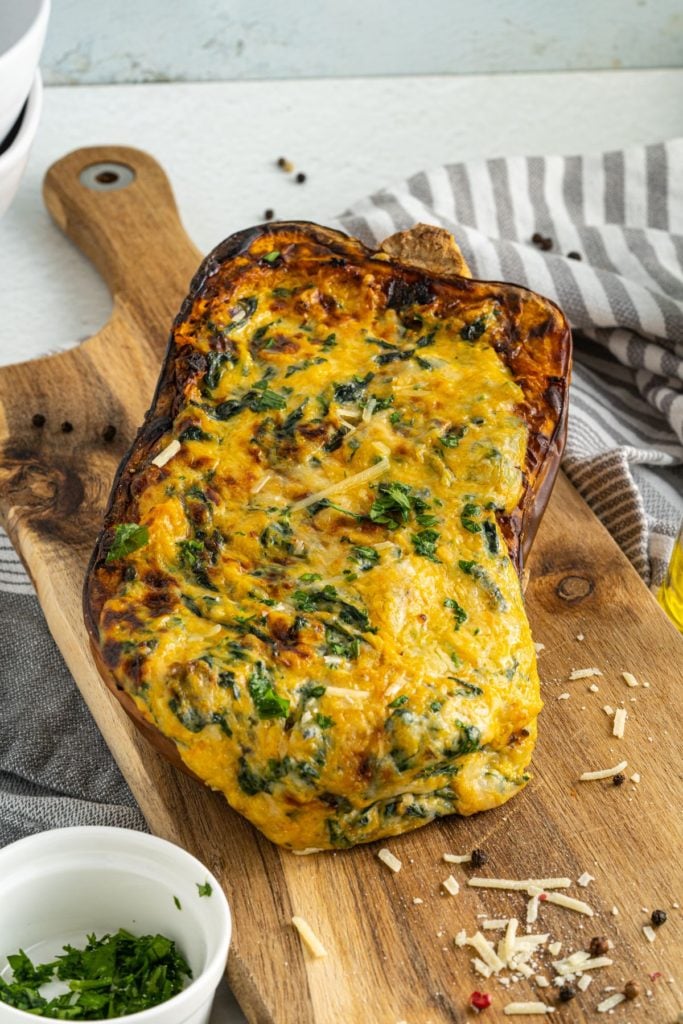 Frontal shot of four cheese stuffed butternut squash on a wooden chopping board