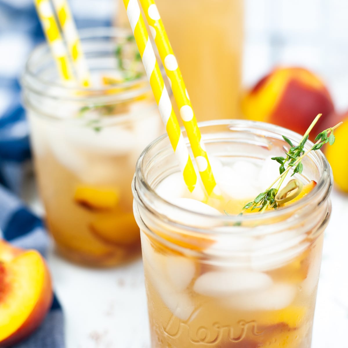 overhead shot of a fresh peach and honey cocktail served in a glass mason jar with some yellow polkadot straws
