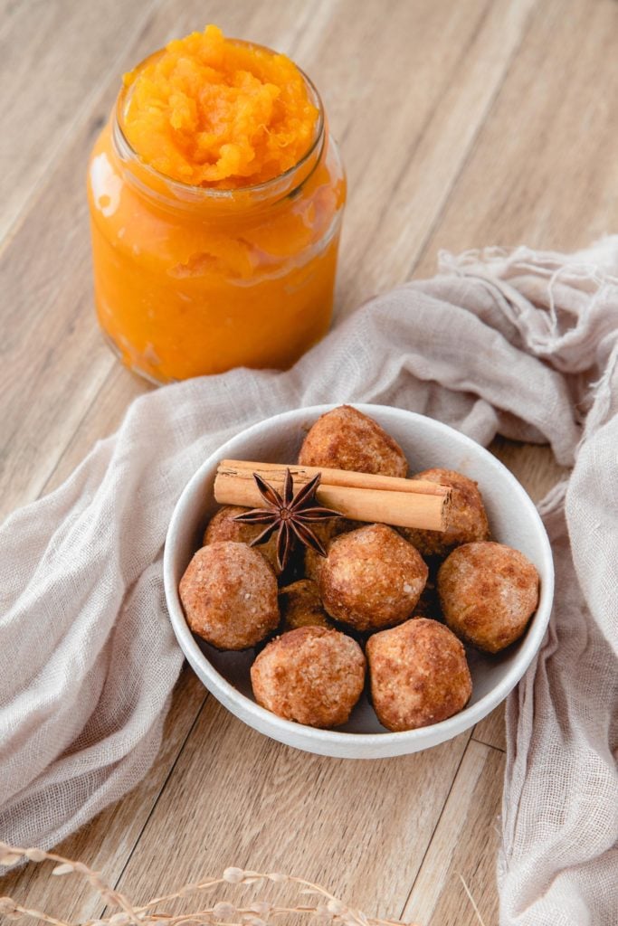 Pumpkin Protein Balls piled in a white bowl and topped with cinnamon sticks and star anise