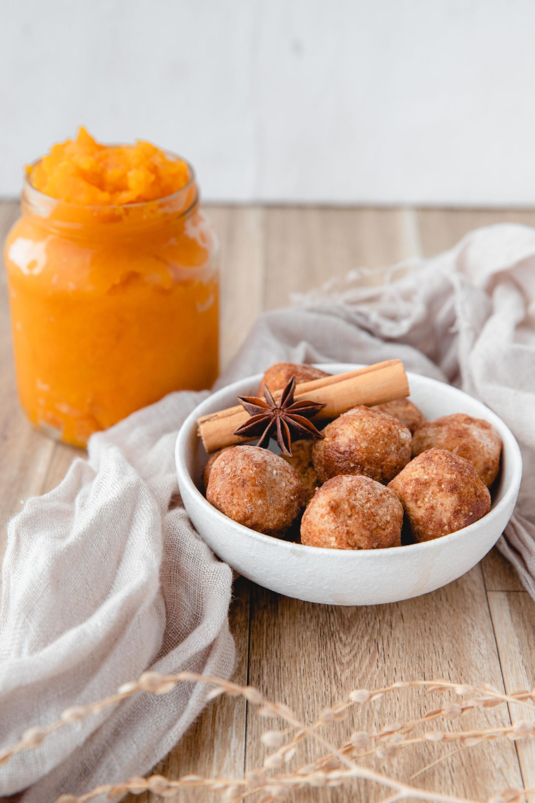 Pumpkin energy balls served in a white bowl with a jar of pumpkin puree in the background