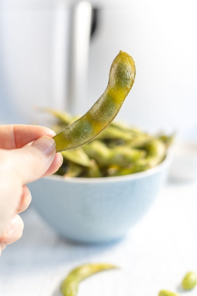 A cooked edamame with soybeans showing through the cooked pod