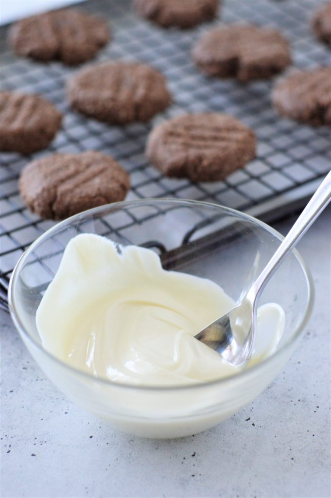 Melted white chocolate in a bowl for topping the almond flour coconut oil cookies