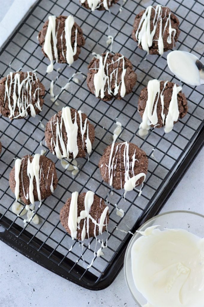 Almond Flour Chocolate Cookies served with a white chocolate drizzle and some white sprinkles on top of a cooling rack