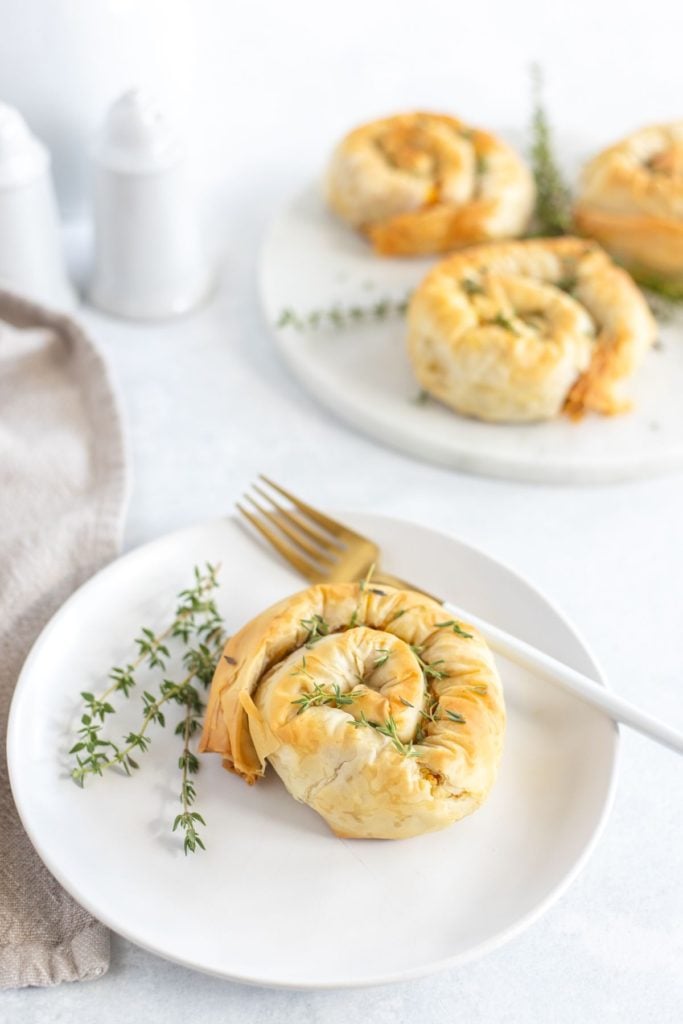 Pumpkin hand pies served on a white plate with fresh thyme sprinkled around