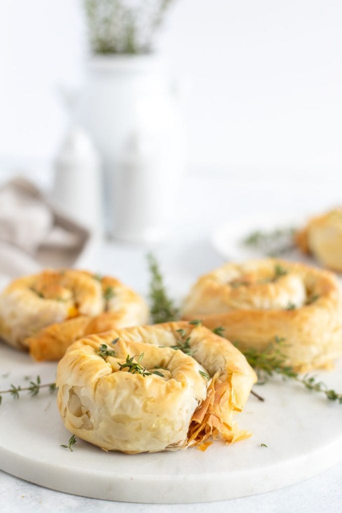 Pumpkin hand pies served on a white plate with fresh thyme sprinkled around