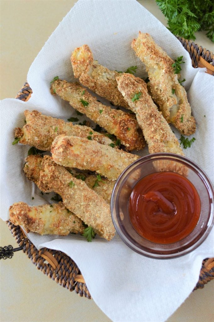 Overhead shot of homemade crispy fish sticks in a serving basket lined with parchment paper.