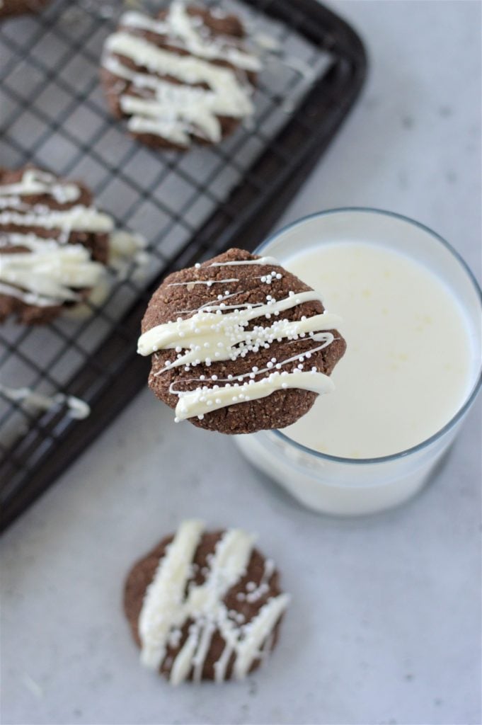 Almond Flour Cookies served with a white chocolate drizzle and some white sprinkles on top of a glass of milk