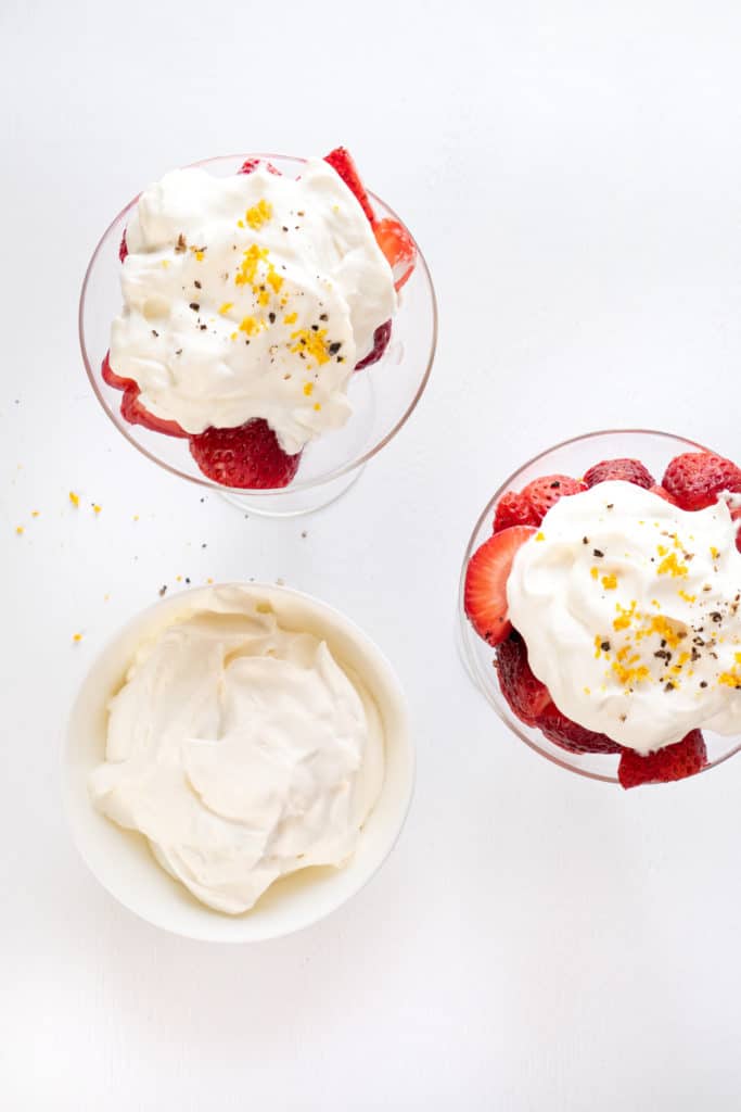 Overhead shot of grand marnier macerated strawberries topped with sweetened whipped cream