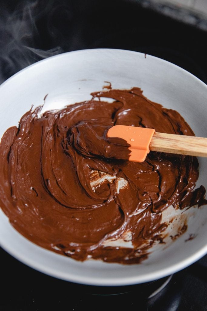 melted chocolate in a white bowl being stirred with a spatula