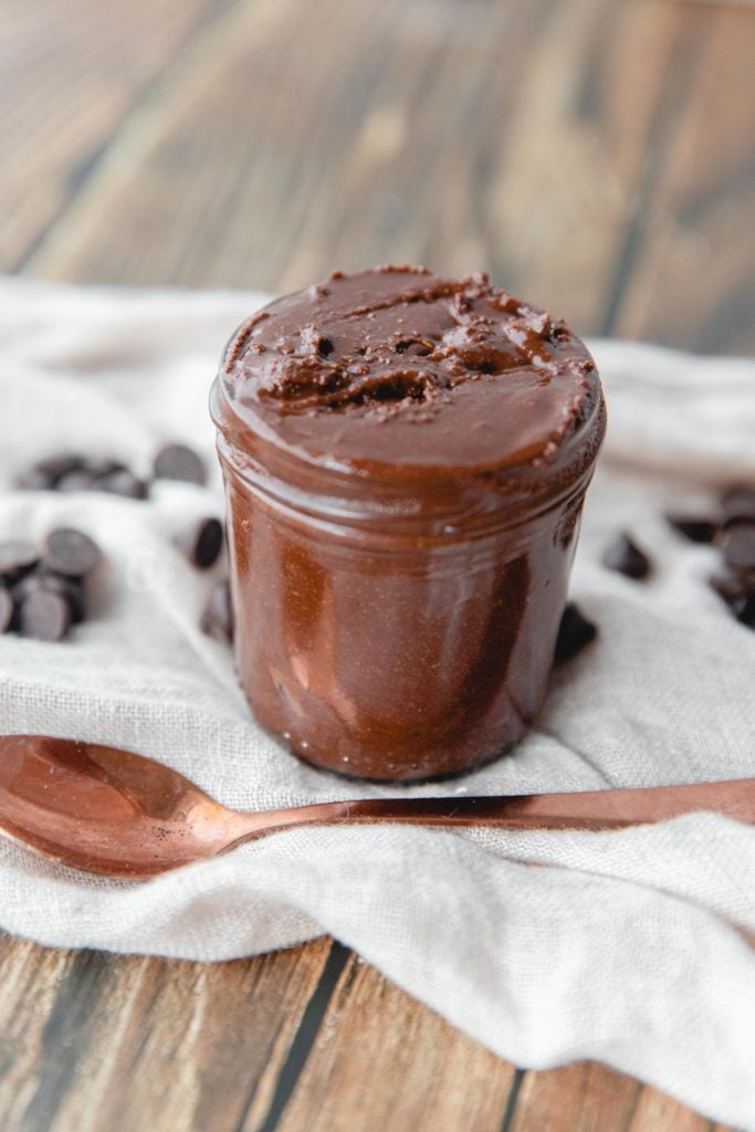 DIY nutella stored in a glass jar with chocolate chips sprinkled on the table