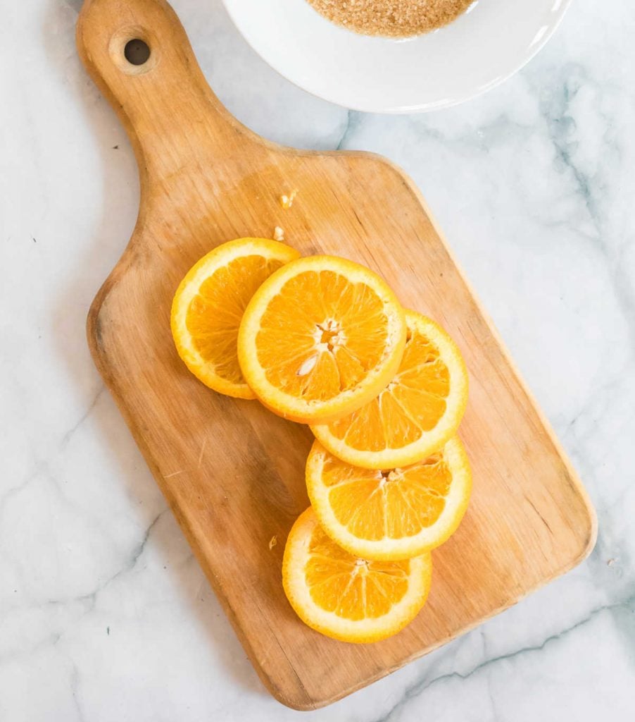 Orange slices on top of a wooden chopping board
