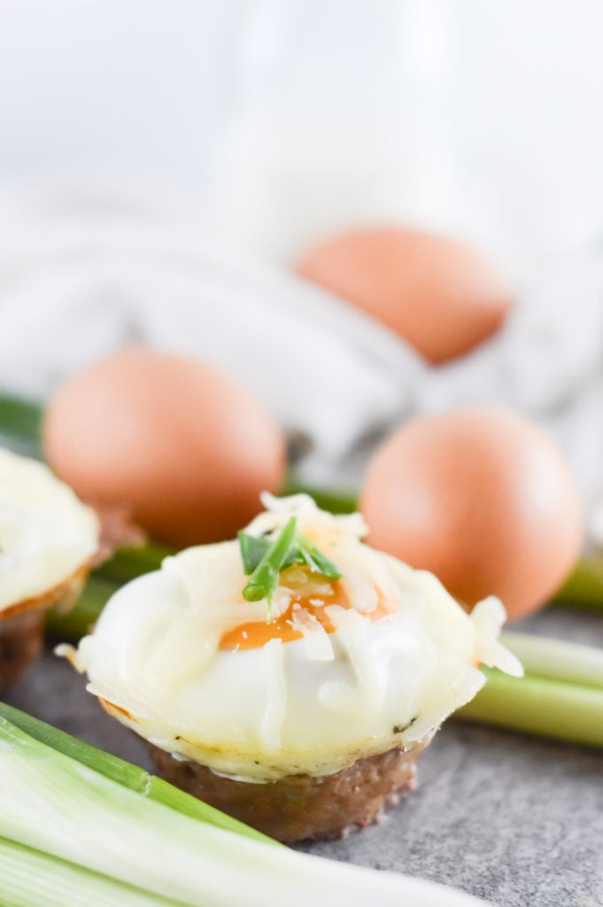 Pork Sausage and Egg Muffin cup with a background of eggs and spring onions