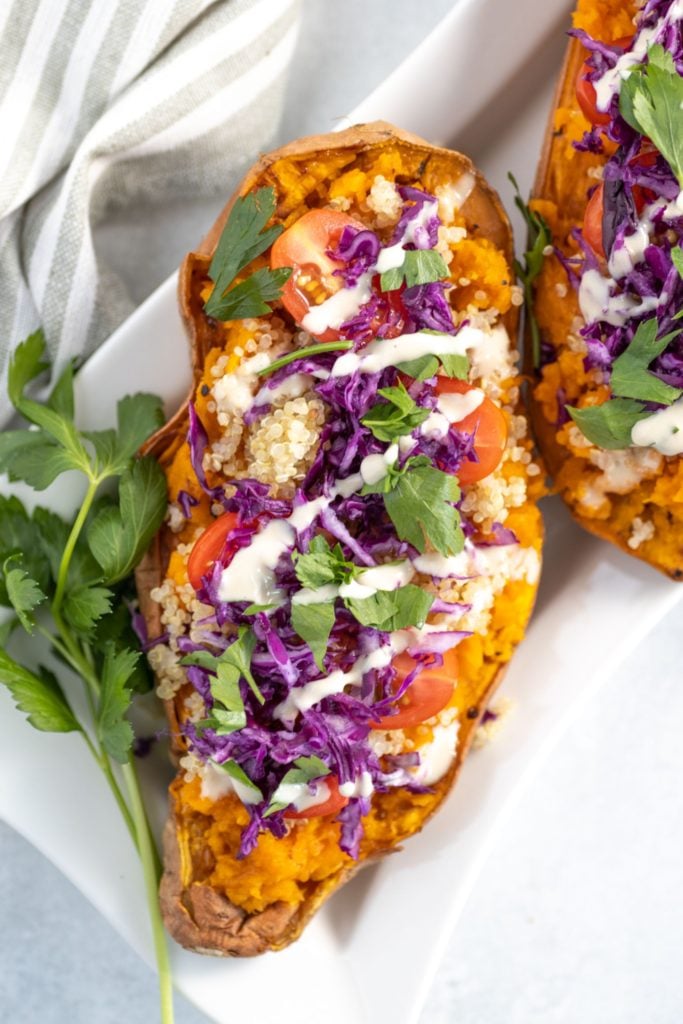 Vegan stuffed sweet potato stuffed with quinoa salad and drizzled with a tahini dressing
