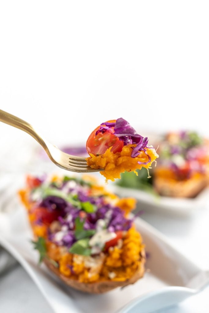 A hand holding a fork getting a spoonful of baked sweet potato and quinoa salad