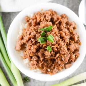 korean style spicy pork mince served in a white bowl with spring onions in the background