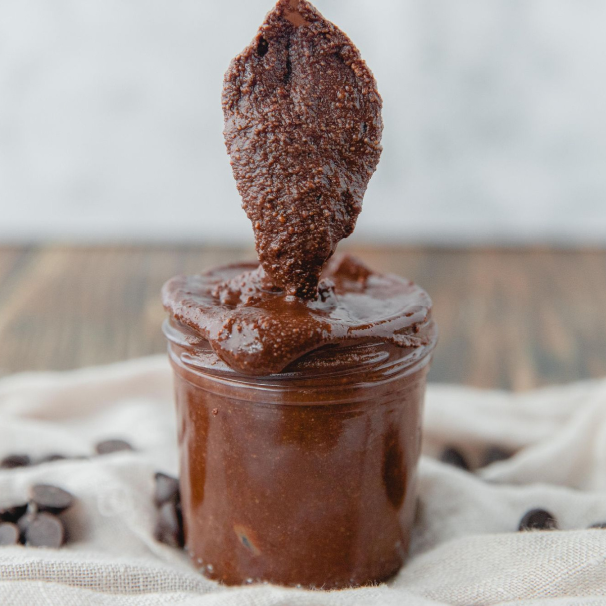 A gold spoon scooping some homemade nutella out of a glass jar