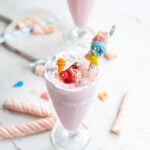 overhead shot of a millkshake in a tall glass topped with lots of candies and marshmallows