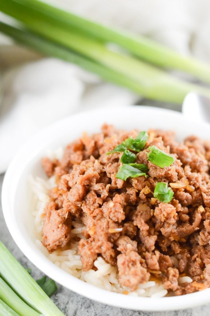 korean style spicy pork mince served in a white bowl with spring onions in the background