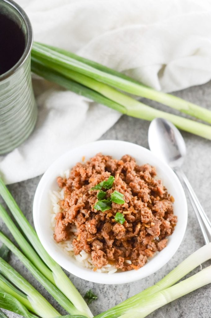 korean style spicy pork mince served in a white bowl with spring onions in the background