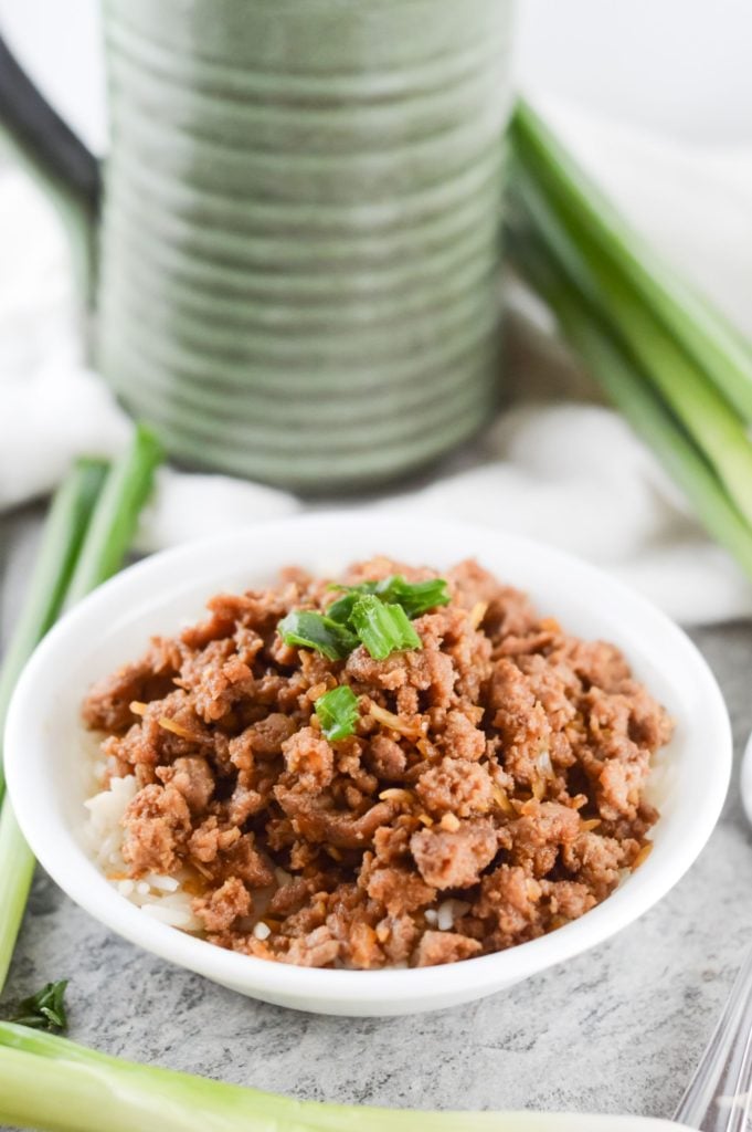 overhead korean style spicy pork mince served in a white bowl with spring onions in the background