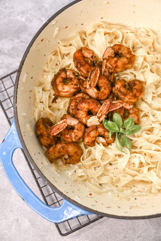 Garlic shrimp pasta in a large crock pot with a sprig of basil
