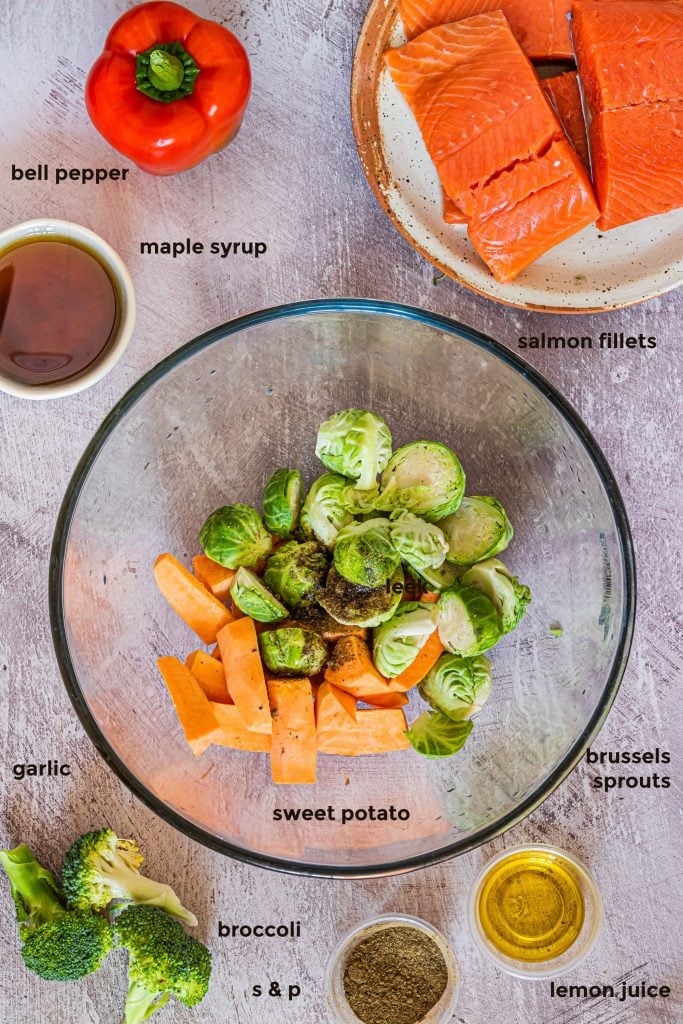 Overhead ingredient shot of salmon, brussels sprouts, bell peppers, broccoli, maple, lime and salt and pepper