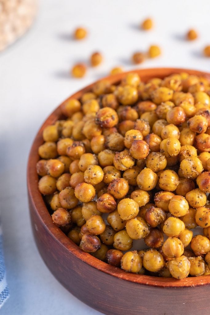 Up close shot of air fryer chickpeas coated in zaatar served in a wooden bowl against a white background