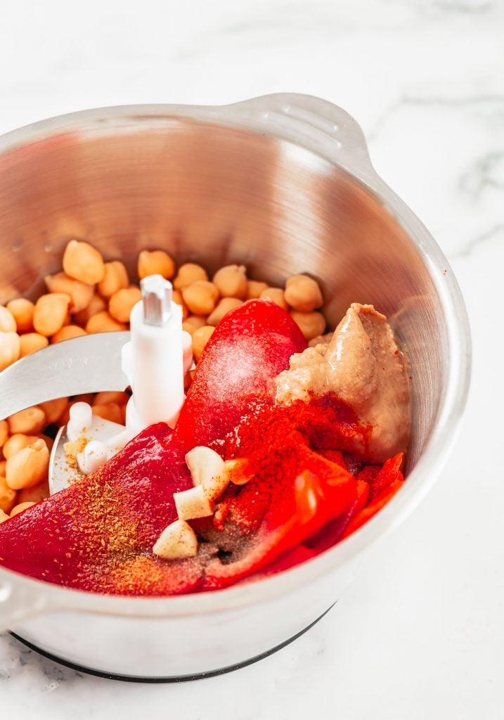 Overhead shot of homemade red pepper hummus in the bowl of a food processor