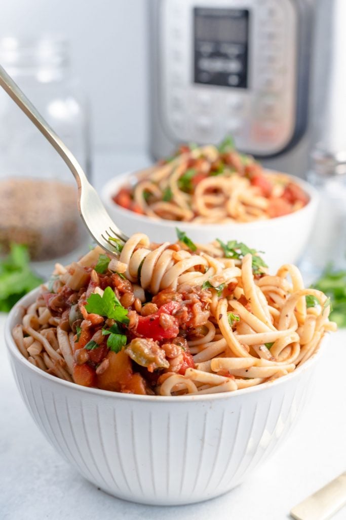 Fork swirling some spaghetti and bolognese from a white bowl