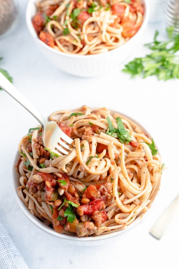 Fork swirling some spaghetti and bolognese from a white bowl