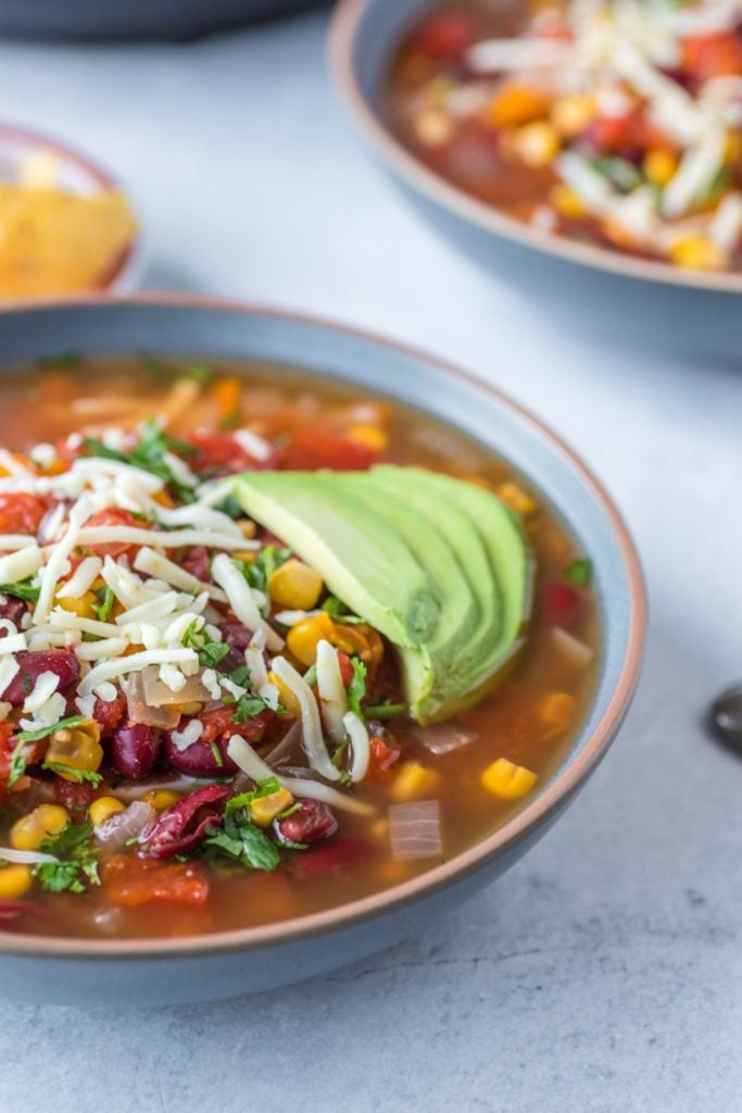 Soup served in a bowl with corn chips in the background