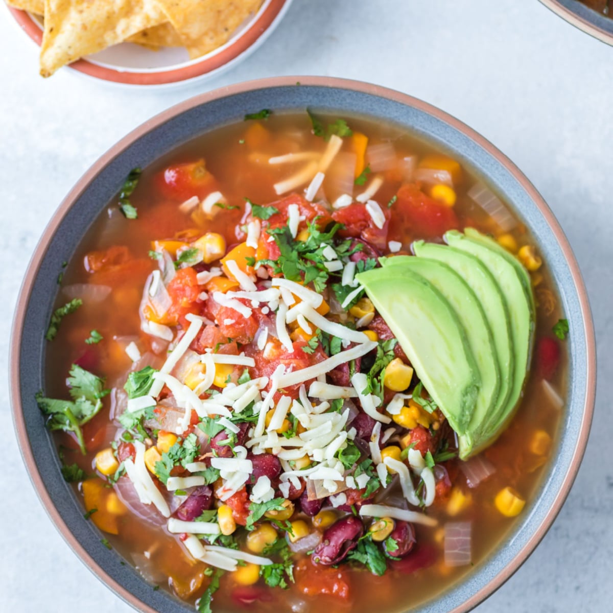 Overhead shot of Vegetarian taco soup loaded up with avocado and shredded cheese