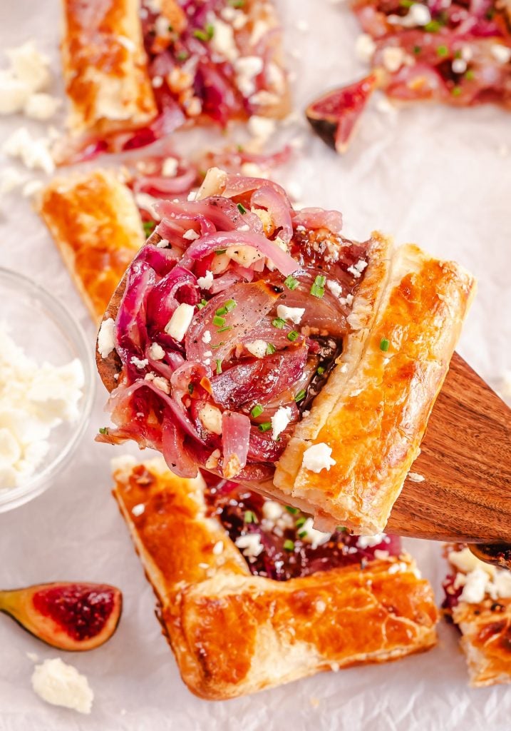 A wooden spatula serving up a slice of onion tart