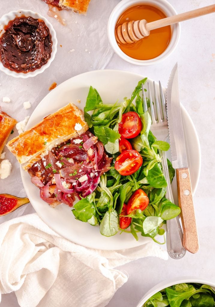 caramelized onion tart served on a white plate with salad