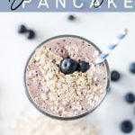 banana blueberry smoothie served in a tall glass with a straw