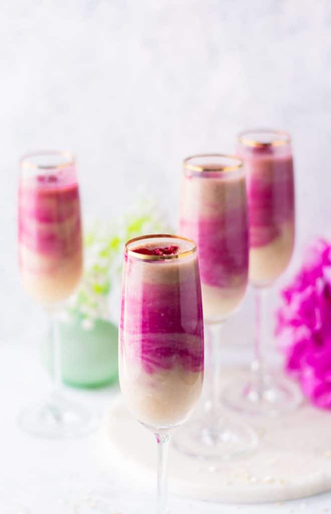 Smoothie table set with 4 pink and white smoothies served in tall glasses