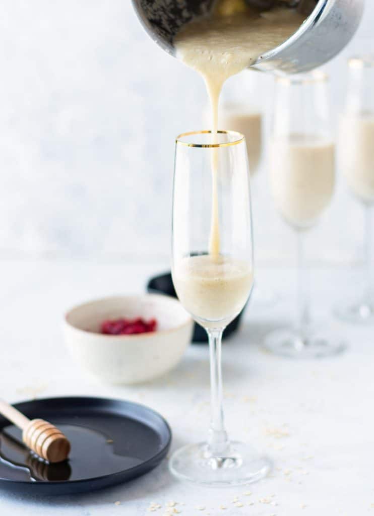 Banana smoothie being poured into a tall skinny glass